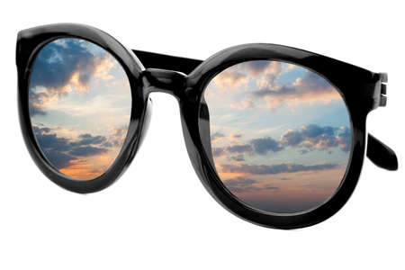 Sunglasses have a sunrise sky with colorful clouds reflecting on isolated white backgroundの写真素材