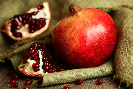 Ripe bright red pomegranate with seeds on wooden and sacking backgroundの写真素材