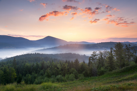 Stunning sunrise mountain landscape with vibrant colors and beautiful fog and clouds formations, summer timeの写真素材
