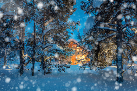 Winter fairytale night snowfall landscape - Wooden house with warm light in night snowy winter forestのeditorial素材
