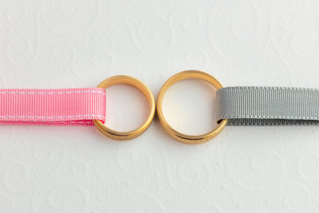 Two Wedding gold rings and ribbons over white decorated paper - wedding stylish backgroundの写真素材