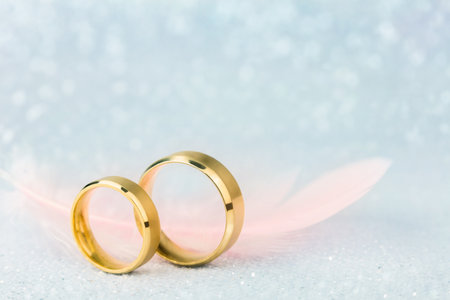 Sparkling Wedding Card - Two Golden Wedding Rings and Light Angelic Feather - gentle soft background for marriageの写真素材