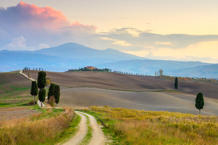 Sunset Landscape with ground road in countryside, fantastic hills and colorful clouds, Tuscany, Italy, Europeの写真素材