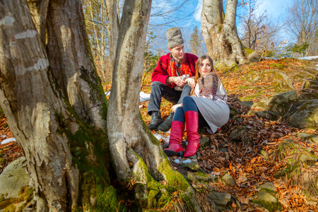 Young couple with traditional local clothes on the natural forest in Carpathians Mountains - fall in love, youth and spring sunny dayの写真素材
