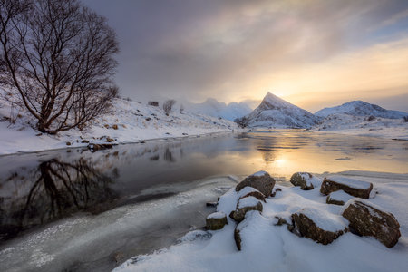 Winter Sunrise with sun reflection on water, mountains covered snow, beautiful Lofoten, Norway, Europe. Large size landscapeの写真素材
