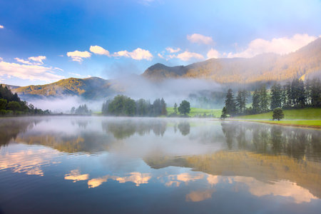 Beatiful morning landscape in Alps mountain and lake with reflections, foggyの写真素材