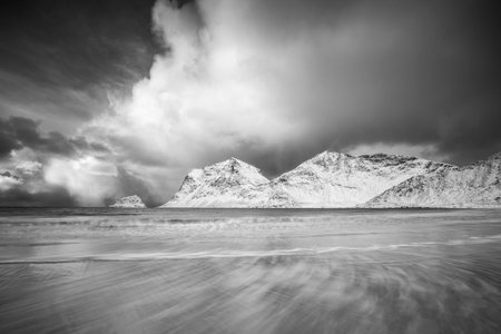 Winter stormy weather at sea and mountains, dramatic clouds and long waves. Northern norwegian landscape. Black and whiteの写真素材