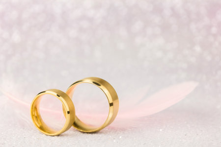 Two Golden Wedding Rings and Light Angelic Feather on sparkling background - gentle soft background for marriage, vintage tonedの写真素材