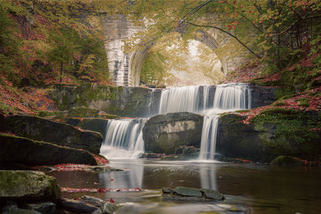 Vintage style Fall Autumn landscape - river waterfall in colorful autumn forest park with yellow red leaves with old bridgeの写真素材