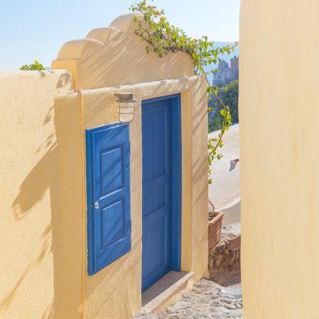 Old blue door and window in the narrow street. Conceptual Artistic Fragments of traditional buildings in Oia on Santorini. A picturesque view of the traditional Santorini cycladic houses on a small street. Oia Village, Santorini, Greece.の写真素材