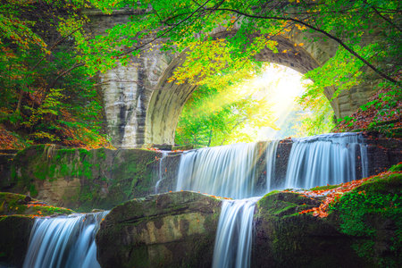 Freshi landscape - river waterfall in colorful mountain forest park with old bridge and sunの写真素材