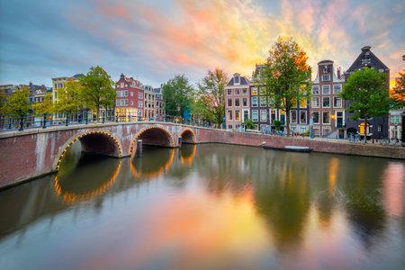 Fantastic sunset sundown sunrise colors in Amsterdam. Panoramic views of the famous old houses, the bridge and the canal in the downtown. Amsterdam, Holland, Netherlands, Europe.の写真素材