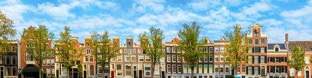 Panorama of the old houses of Amsterdam on the background of the blue sky. Roofs of houses, windows and facades. The houses of Amsterdam are famous all over the world. Panoramic Background or Frame. Amsterdam, Holland, Netherlands, Europeの写真素材