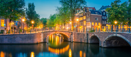 Romantic Amsterdam lit the lights. Evening view of the famous historic center with lantern lights, bridges, canals and cute Dutch houses. Amsterdam, Holland, European travel. Panoramicの写真素材