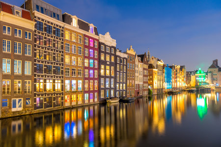 Panoramic view of Famous old houses of Amsterdam. The houses stand in the water and have a beautiful reflection at night. Touristic district Damrak. These houses are famous all over the world. Amsterdam, Holland, Europeの写真素材