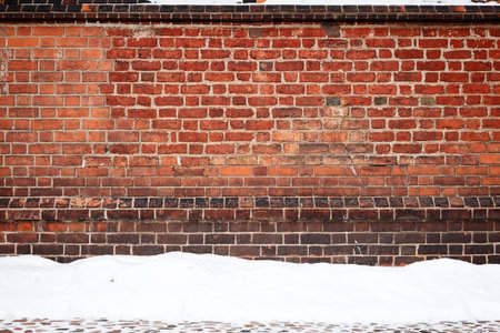 Old wall of stone bricks and a ground covered with snowの写真素材