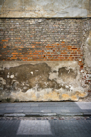 Old weathered wall of bricks and a sidewalkの写真素材
