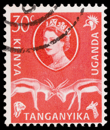 UGANDA - KENYA - TANGANYIKA - CIRCA 1954: A stamp printed in Uganda - Kenya - Tanganyika shows Elizabeth II Queen Great Britain and antelopes, circa 1954 のeditorial素材
