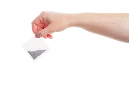 Female hand holding teabag isolated on white の写真素材