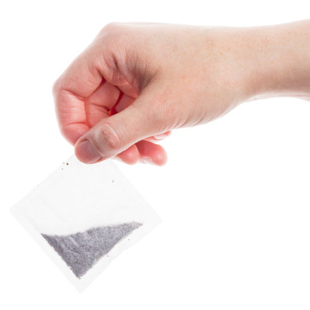 Female hand holding teabag isolated on white backgroundの写真素材