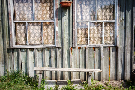 Old wooden house facade with windows and bench の写真素材