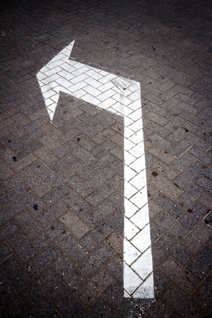 White directional arrow sign on a road