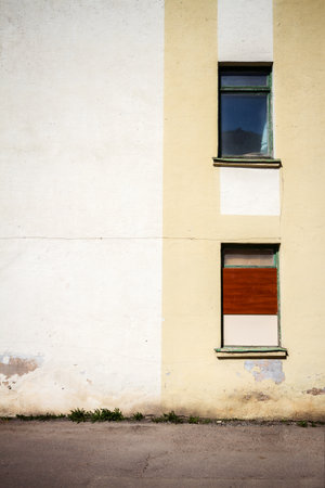 Yellow wall of a abandoned house with two windows