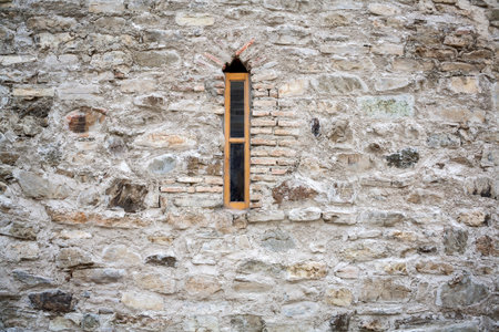 Wall of stones with a small window in a middleの写真素材