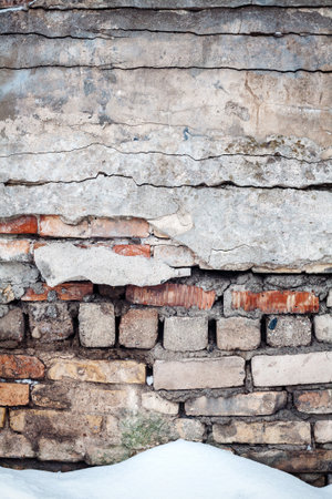 Old cracked wall of bricks and snowの写真素材
