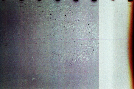 Blank grained film strip texture background with heavy grain, dust, scratches and light leakの写真素材