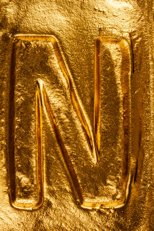 Beautiful handmade letter N on a shiny gold textureの写真素材