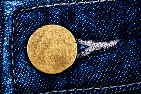 Macro image of old grungy brass button of blue jeans texture