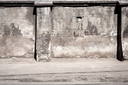 Old gray cracked plaster fence and sidewalkの写真素材