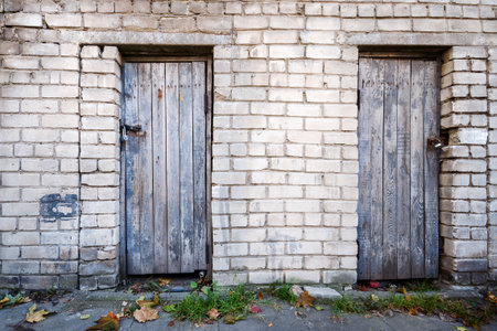 Two old wooden plank doors in a brick wallの写真素材