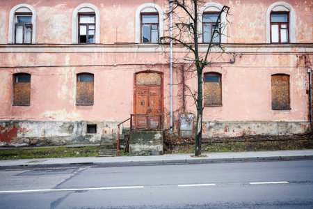 Abandoned weathered pink street wall with some windows and doorsの写真素材