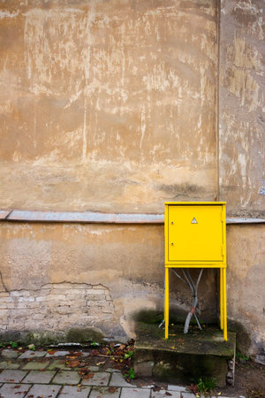 Yellow power supply box on a old plaster wallの写真素材