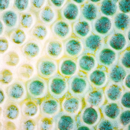 Closeup shot of glazed green and yellow ceramics textureの写真素材