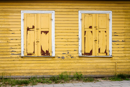 Old yellow wooden plank wall with some windowsの写真素材