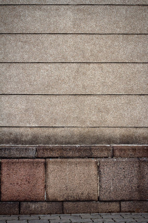 Aged weathered lined plaster street wall with stone tile basement. Architecture detail backgroundの写真素材