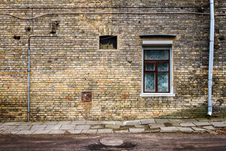 Aged weathered street wall with a windows. Architecture detail background. Old yellow brick wallの写真素材