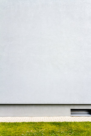 Modern light blue plaster wall with green grassの写真素材