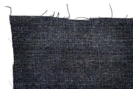 Piece of dark jeans fabric isolated on white background. Rough uneven edges.