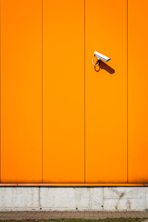 Orange wall of the building, warehouse and the security camera. Surveillance system on the wall...