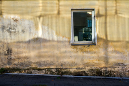 Old cracked yellow wall and sun reflection from windows on itの写真素材