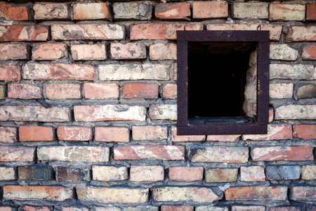 Old brick wall with a small window with rusty iron frame