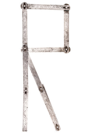 Old iron meter ruler. Old iron folding meter in the shape of letter R isolated on white background.の写真素材