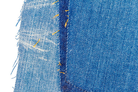 Piece of blue jeans fabric with a ripped of back pocket isolated on white background. Rough uneven...