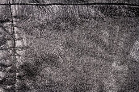 Crumpled black leather texture background. Abstract texture of leather with a seam.