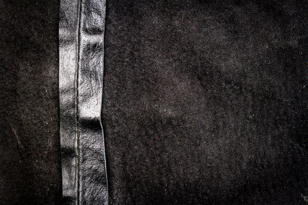 Crumpled black leather texture background. Abstract texture of leather with a seam. Back side