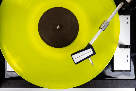 Close up of vintage turntable vinyl record player with yellow vinylの写真素材